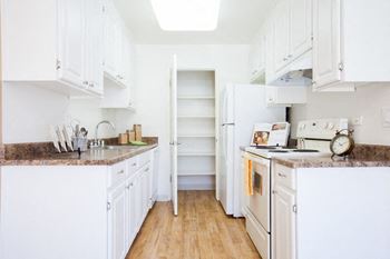 A kitchen with white cabinets and a white refrigerator